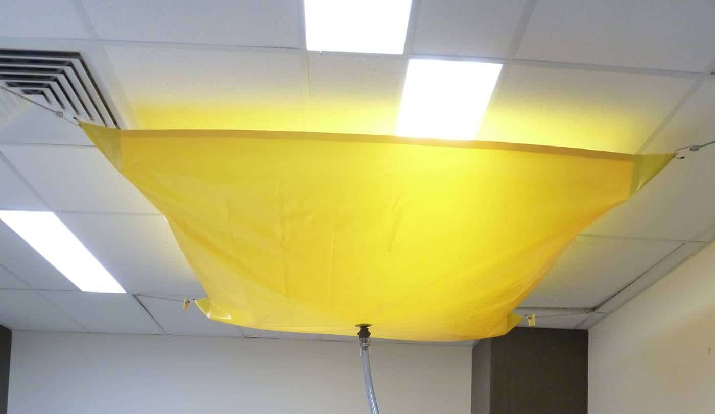 Chatoyer Roof Leak Diverter made from yellow PVC and hanging from the ceiling in an office building